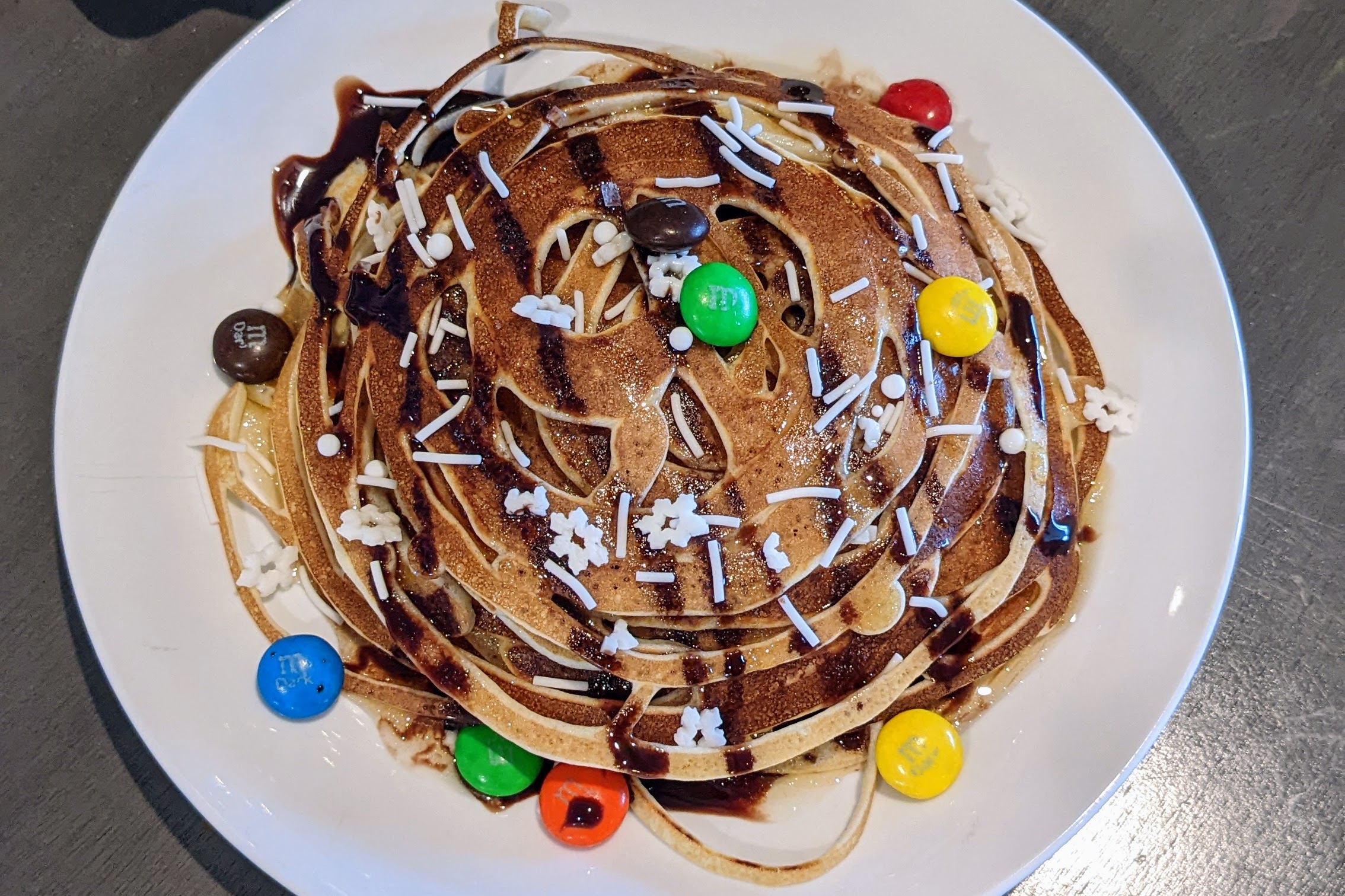 squiggly buddy-inspired breakfast pancakes with chocolate syrup, sprinkles, M&m's and maple