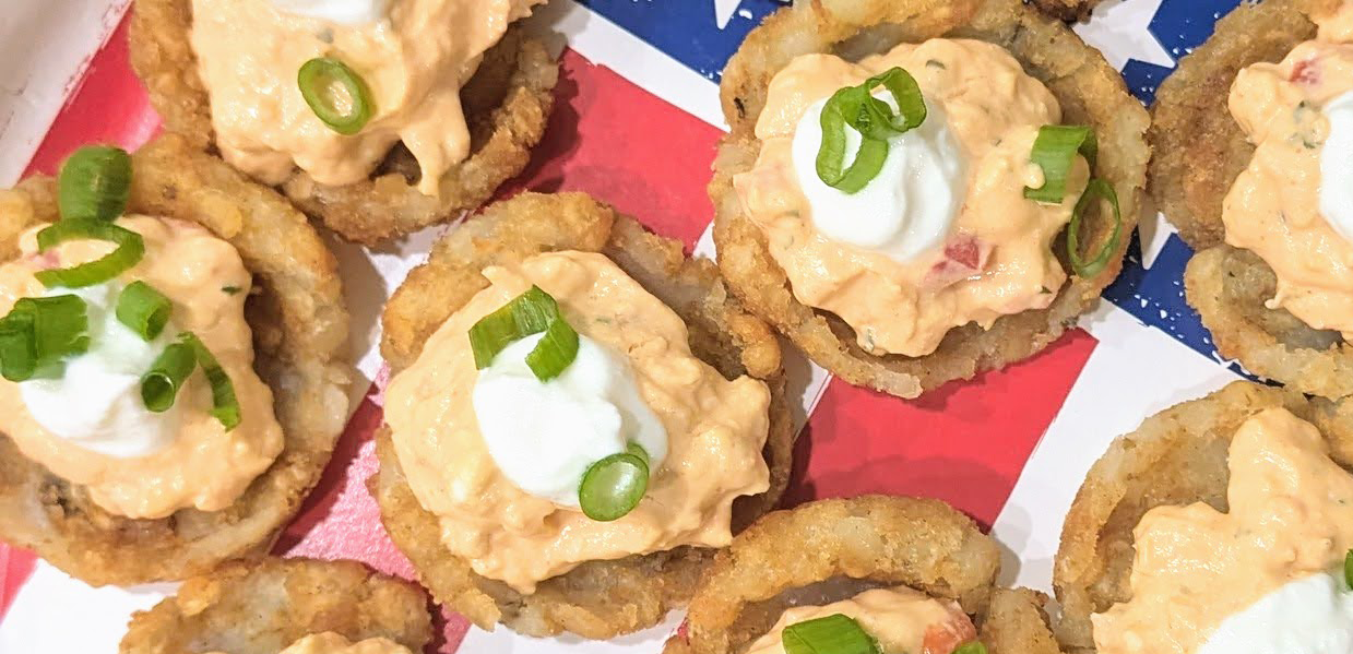 buffalo chicken tots featuring buffalo chicken dip and sour cream atop smashed tater tots